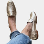 Shiny gold slip-on loafers with strap across the top