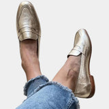Shiny gold slip-on loafers with strap across the top