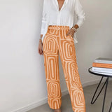 Two-piece outfit: white blouse with belt; wide-leg orange pants with cream abstract pattern