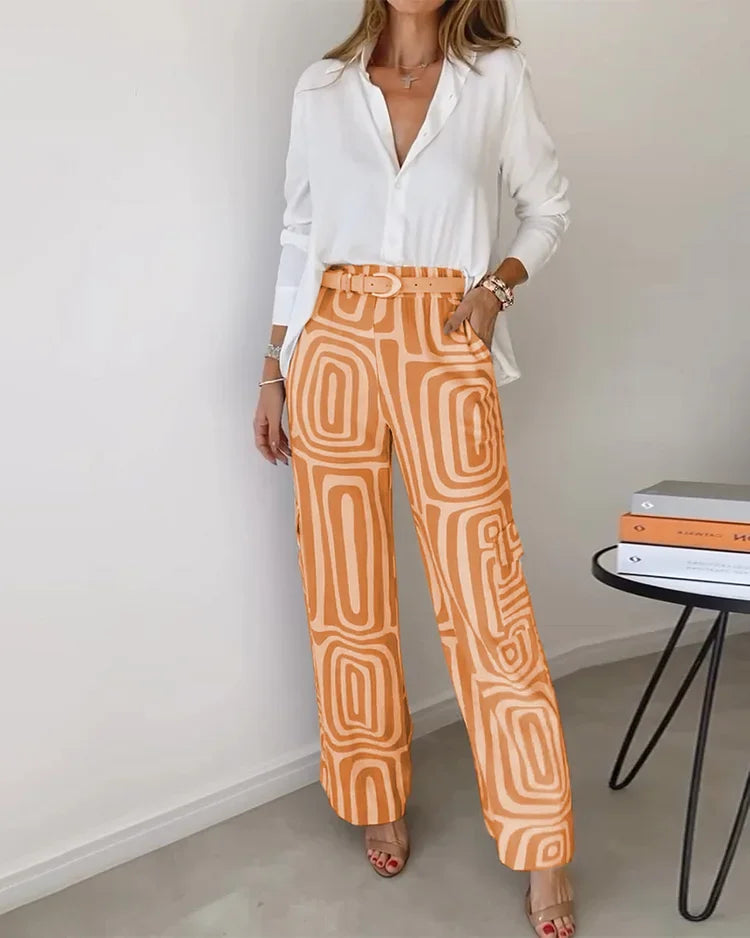 Two-piece outfit: white blouse with belt; wide-leg orange pants with cream abstract pattern