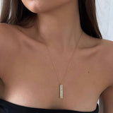 Gold-tone pendant necklace with rectangular clear-stone bar charm at center