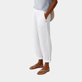 White linen-effect pants with elastic waist, button detail, and cuffed ankle hems