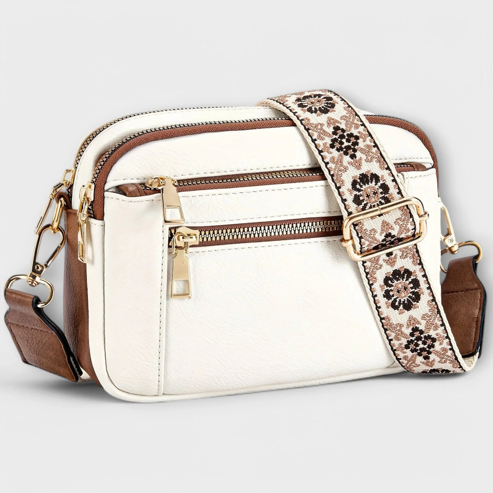 White small crossbody bag with flap front, front zipper, and floral patterned strap.