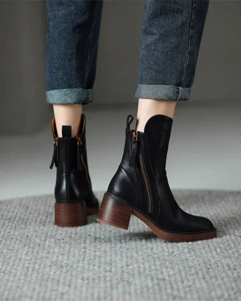 Black leather ankle boots on floor, side zipper detail and block heel