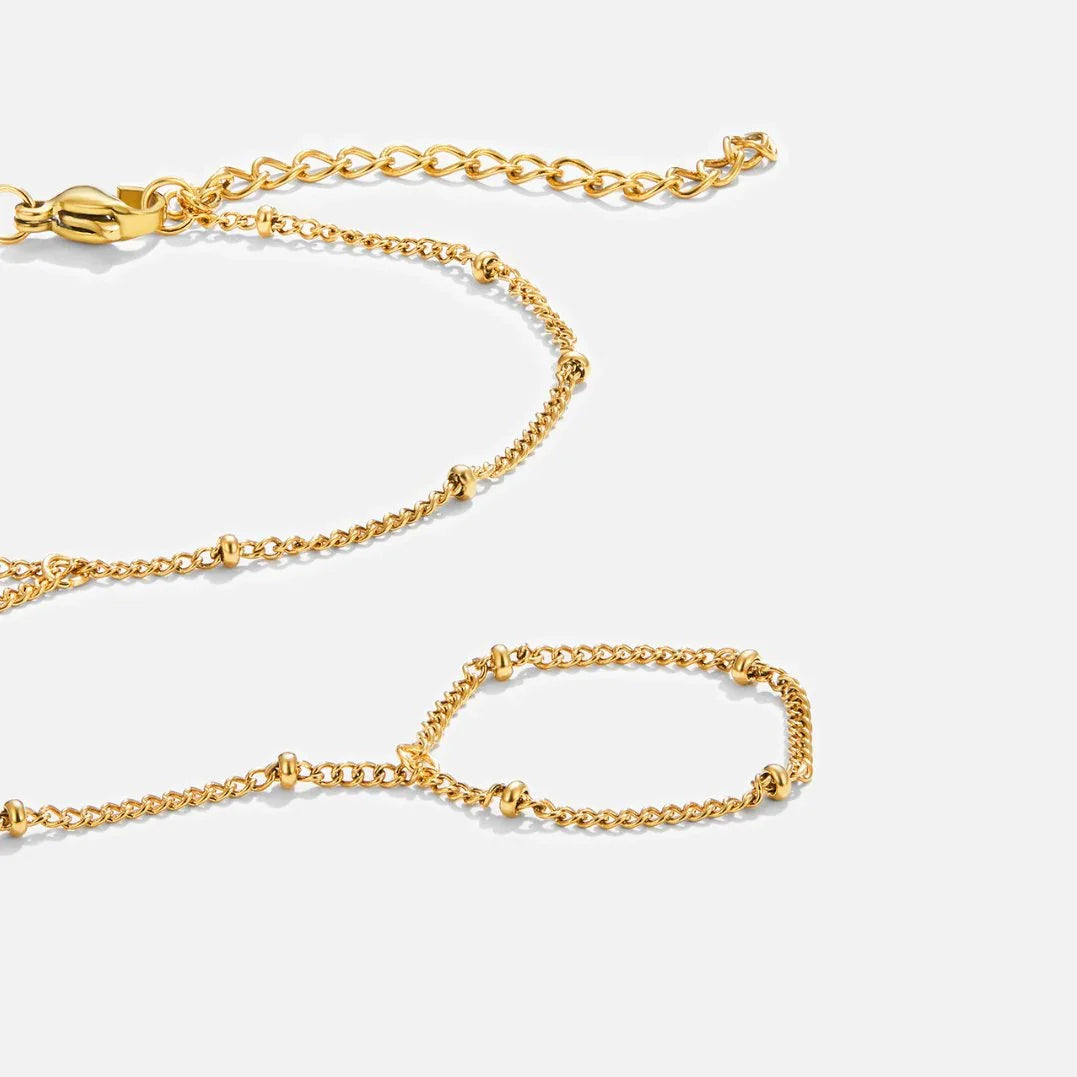 Close-up of gold chain hand bracelet with interlocking links and small bead details