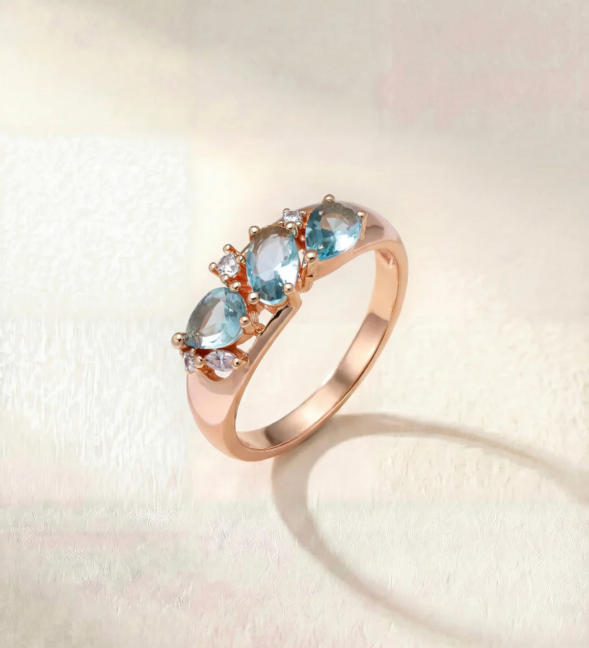 Rose gold wave-style ring with three light blue gemstones on band