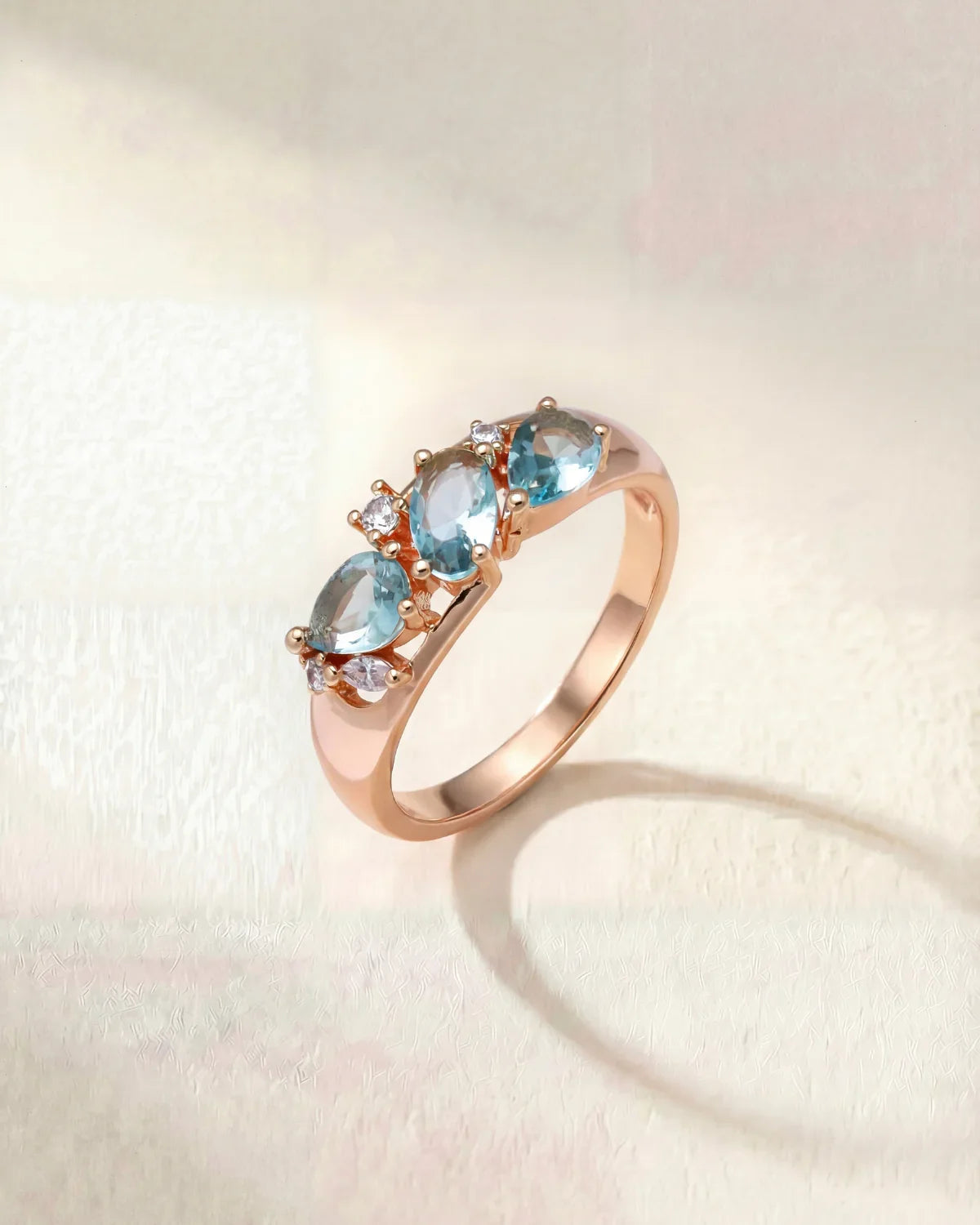 Rose gold wave-style ring with three light blue gemstones on band