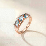 Rose gold wave-style ring with three light blue gemstones on band