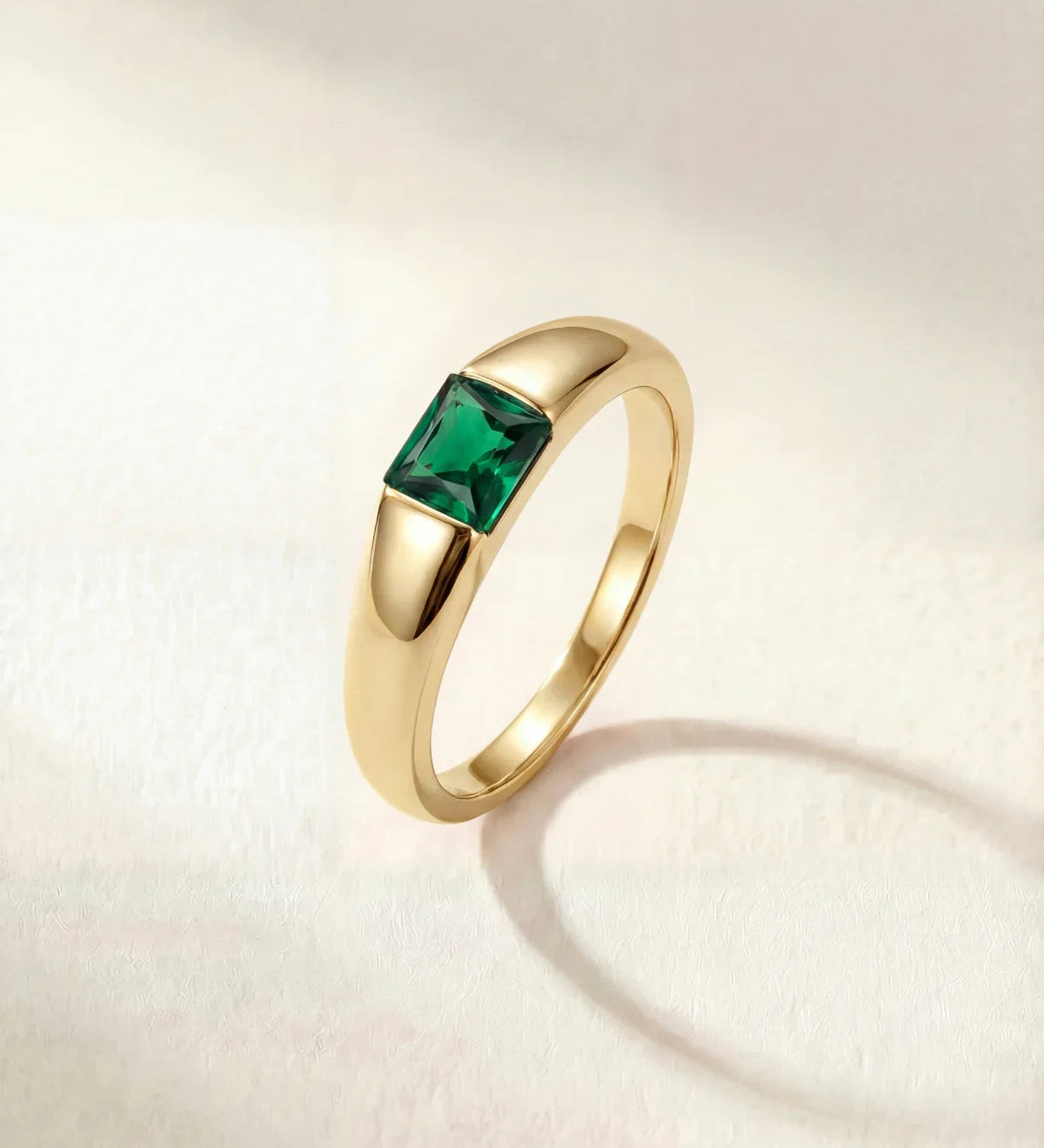 Gold-tone ring with a square green gemstone set on a tapered band
