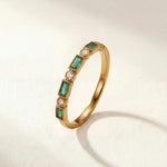 Gold ring with green rectangular stones and small clear accents on a thin band