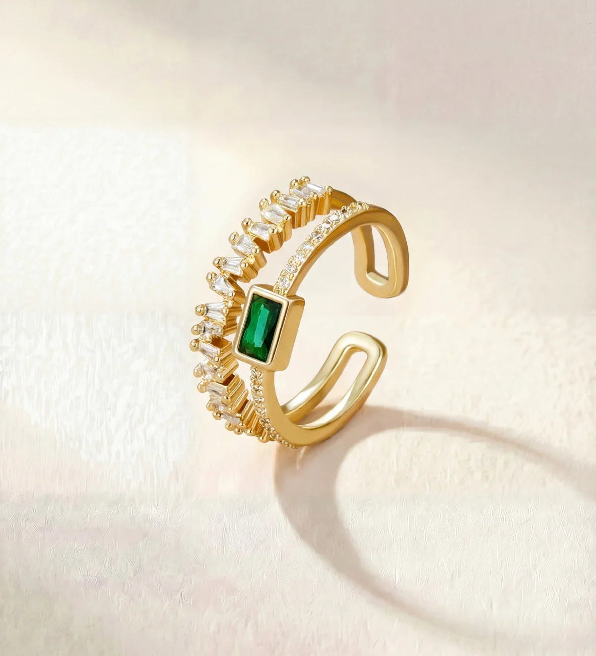Gold ring with green square center stone and clear halo stones, adjustable band