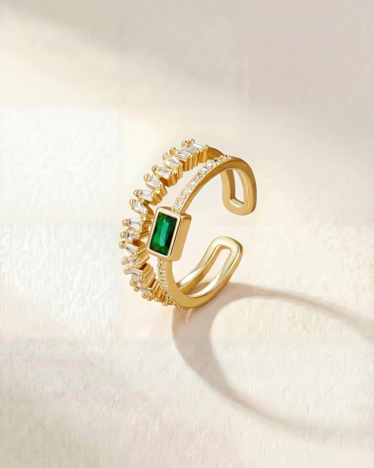 Gold ring with green square center stone and clear halo stones, adjustable band
