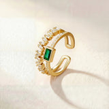Gold ring with green square center stone and clear halo stones, adjustable band