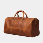 Caramel leather travel bag with structured sides, top handle, and corner strap