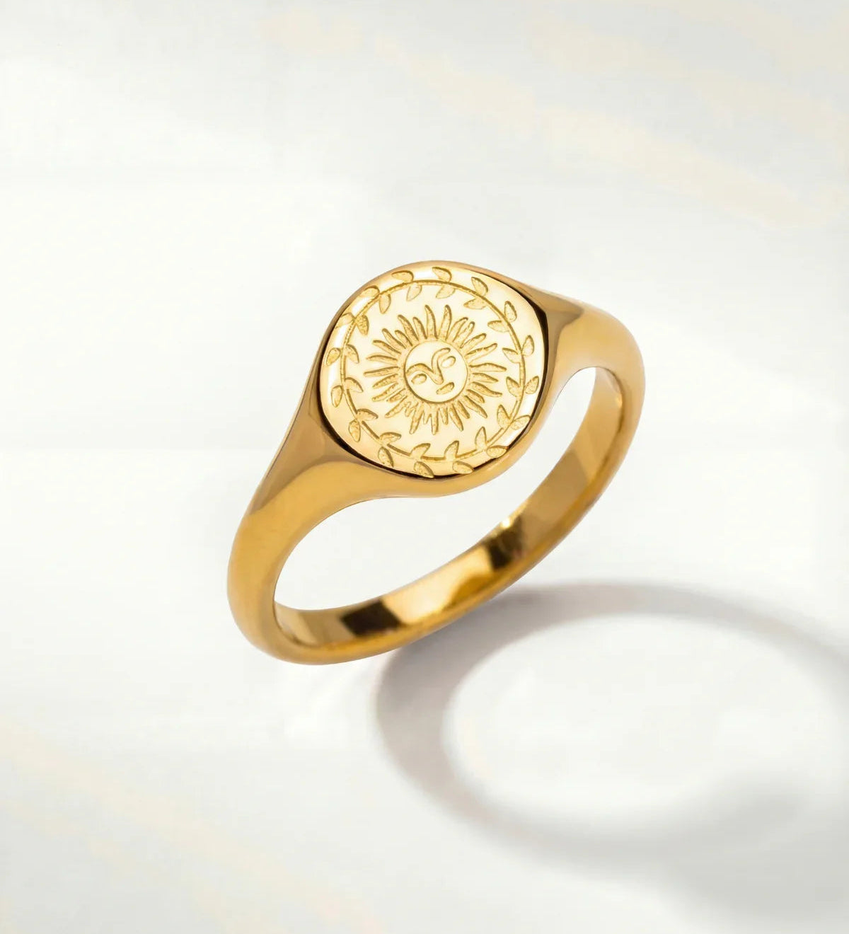 Gold-tone ring with oval sunburst engraving on the top and a smooth band