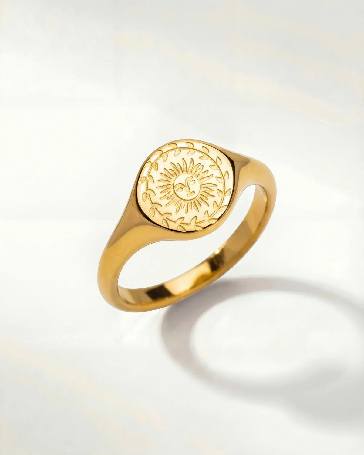 Gold-tone ring with oval sunburst engraving on the top and a smooth band