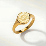 Gold-tone ring with oval sunburst engraving on the top and a smooth band