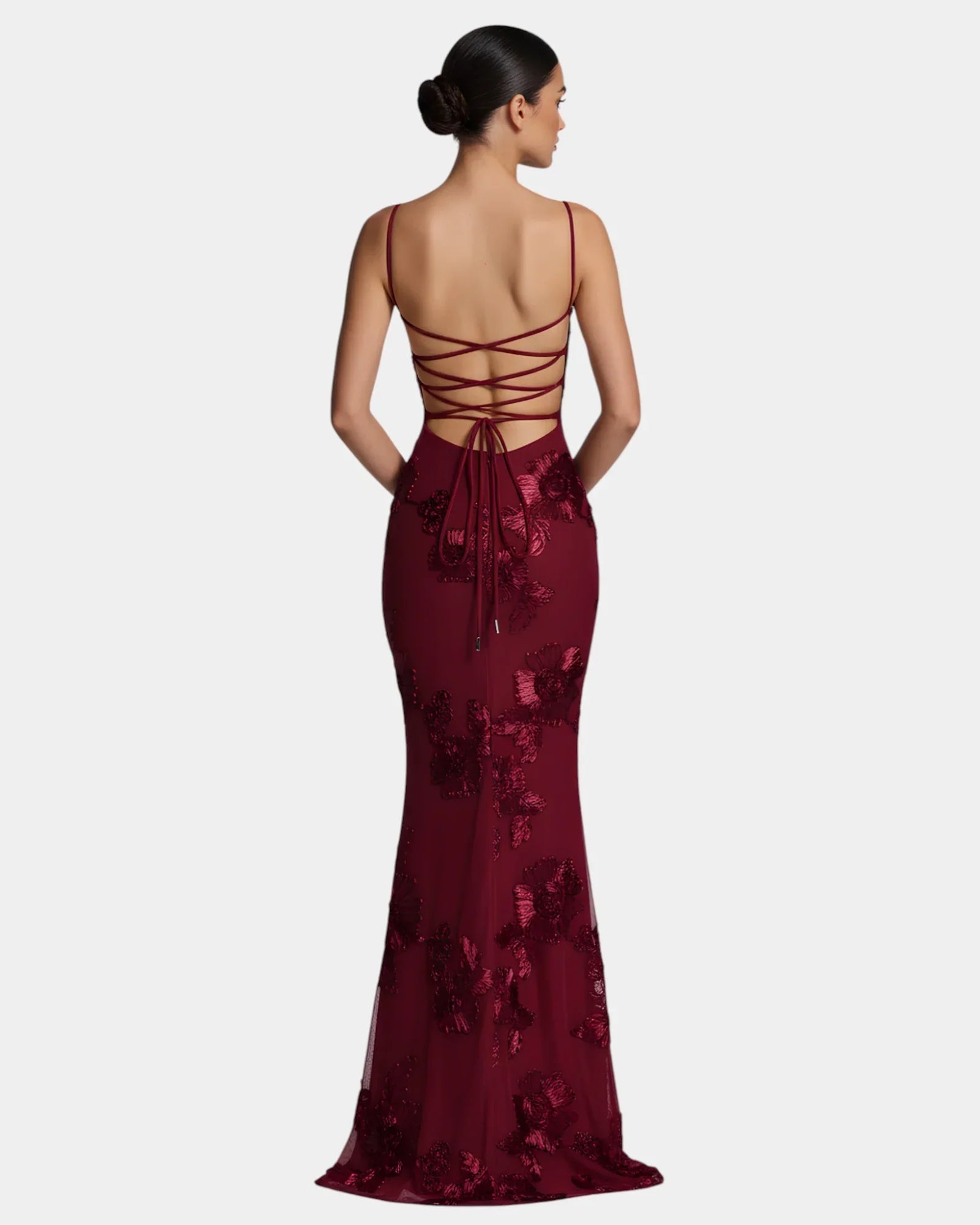 Burgundy floor-length gown with spaghetti straps, lace-up back, and floral embellishment