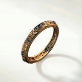 Gold ring with blue gemstones, ornate bezel and textured band