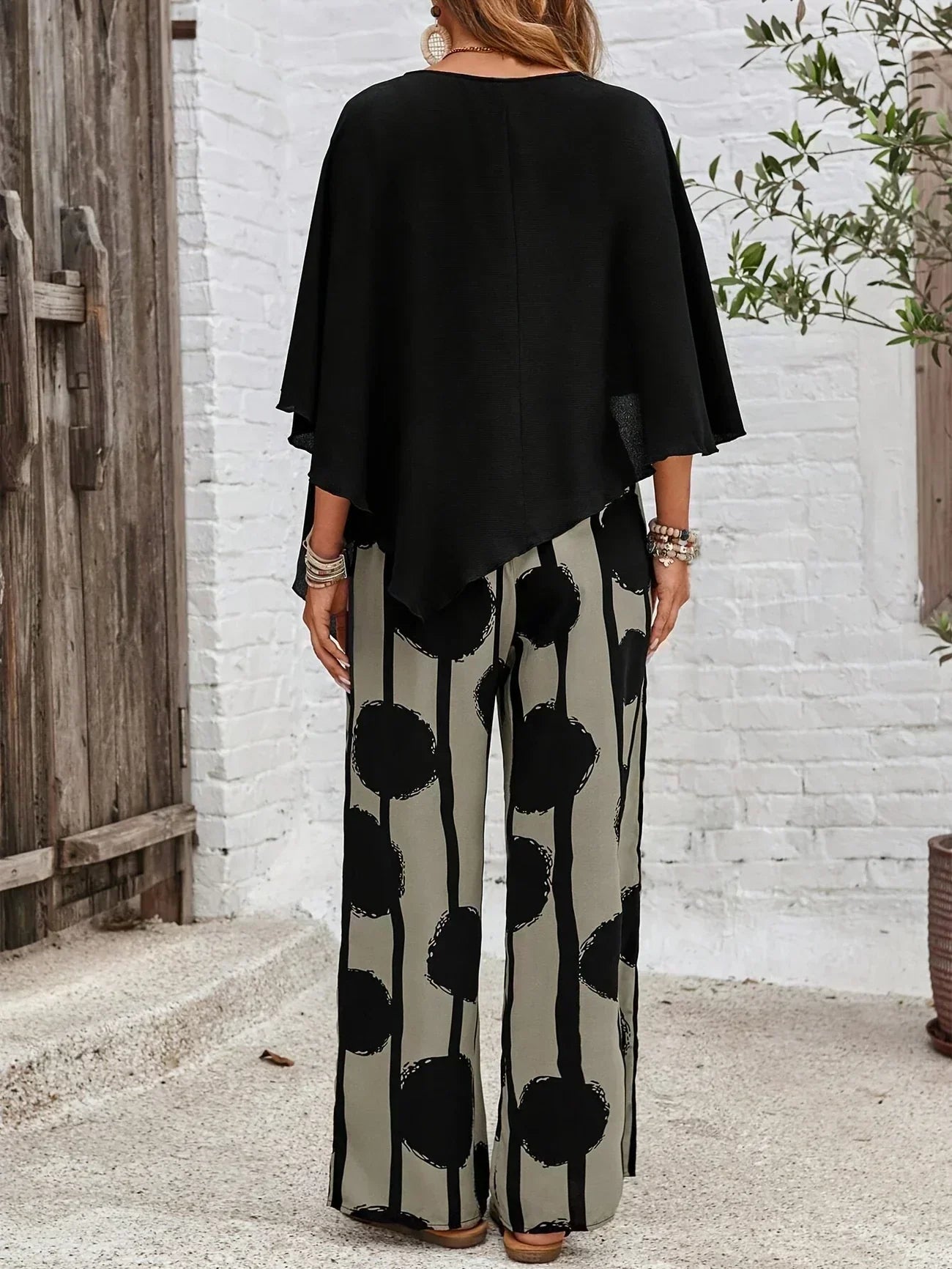 Back view: black asymmetrical top with batwing sleeves and wide-leg boho pants in dot print