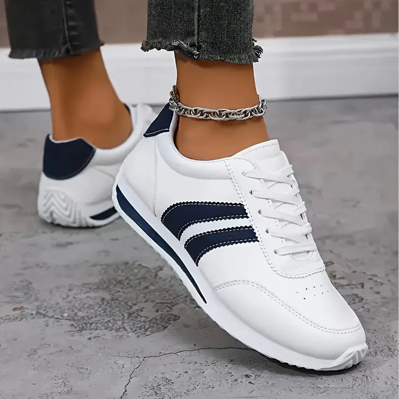 White lightweight orthopedic sneakers with navy stripe accents and low-profile sole
