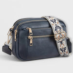 Navy small crossbody bag with flap front, front zipper, and floral patterned strap.
