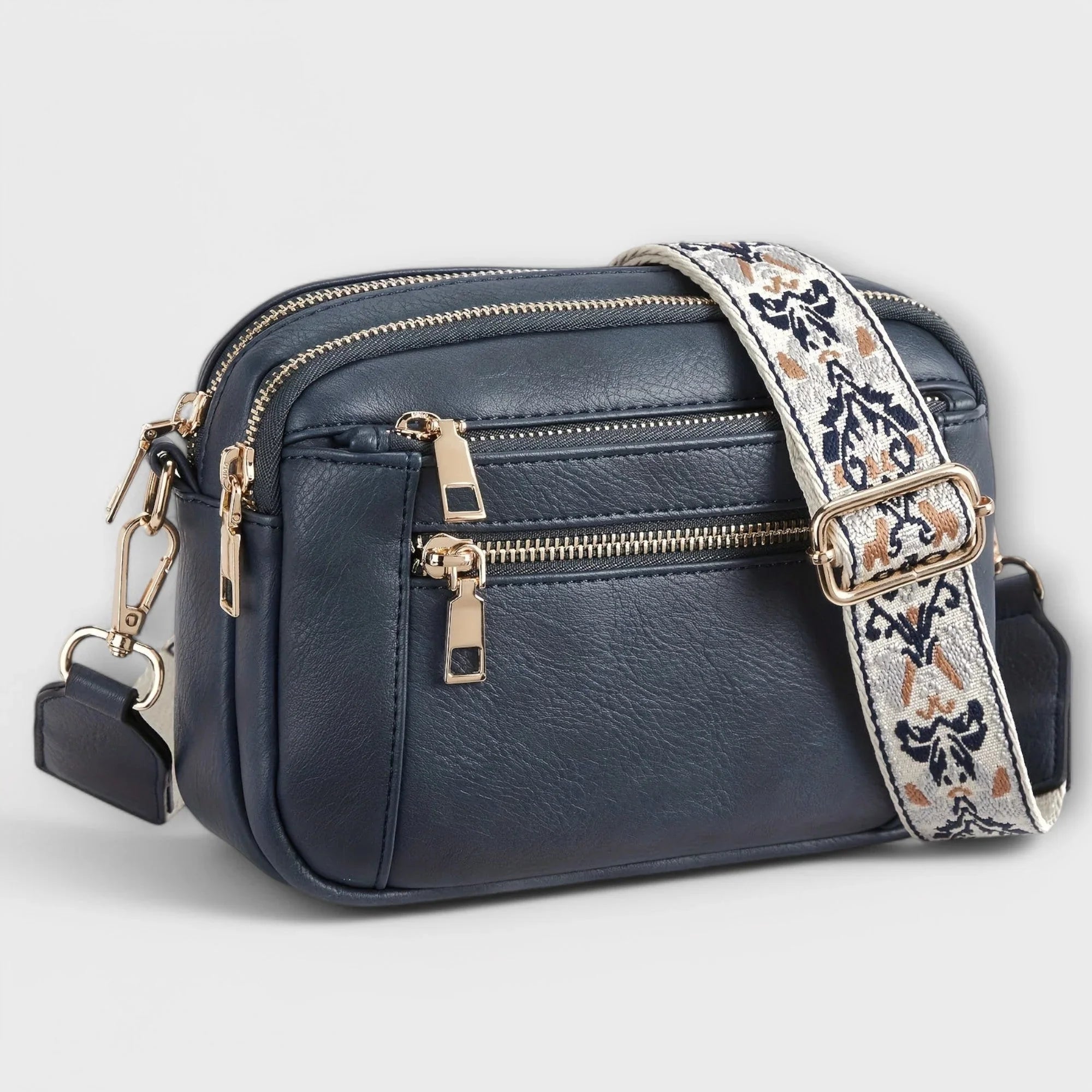 Navy small crossbody bag with flap front, front zipper, and floral patterned strap.