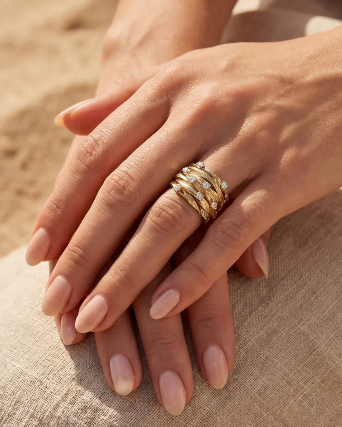 Gold-tone ring on fingers with clear stone rows and braided-style band texture