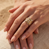 Gold-tone ring on fingers with clear stone rows and braided-style band texture