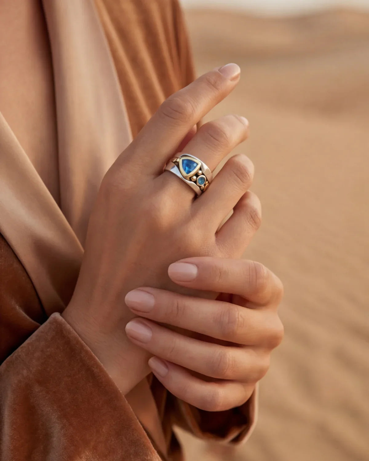 Silver ring with blue oval stone, gold-toned bezel, and swirl-style detail