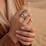Silver ring with blue oval stone, gold-toned bezel, and swirl-style detail