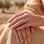 Gold band ring featuring green rectangular stones with small clear side accents