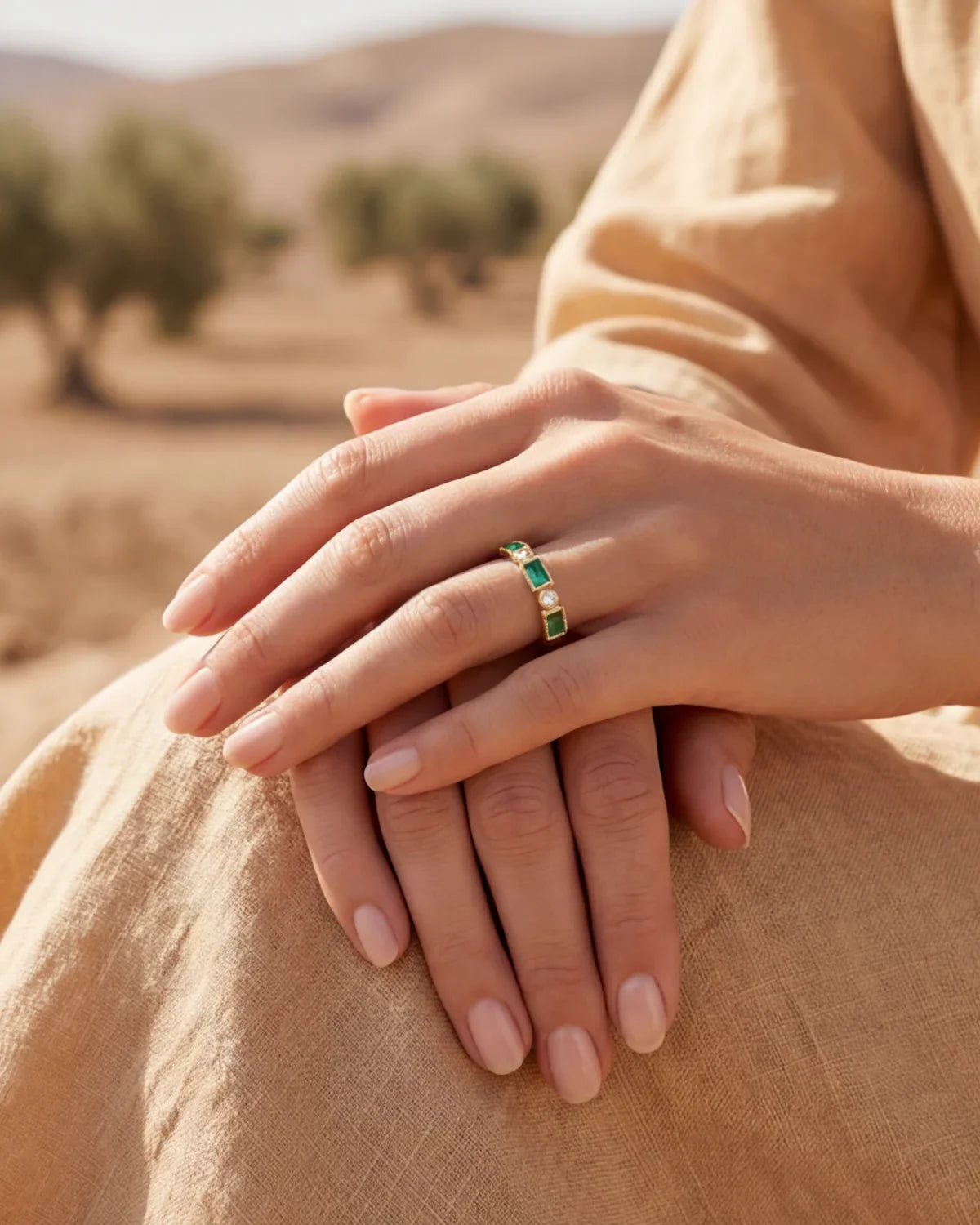 Gold band ring featuring green rectangular stones with small clear side accents