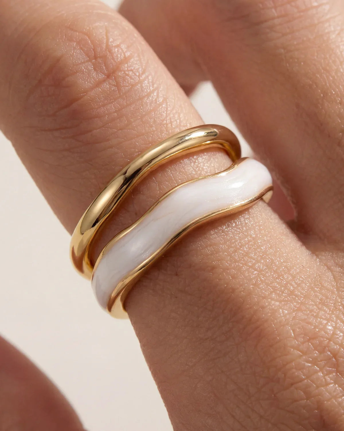 Adjustable gold ring with white inlay stripe, side view on hand
