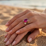 Livia sapphire ring on hand, gold band with vibrant magenta oval gemstone