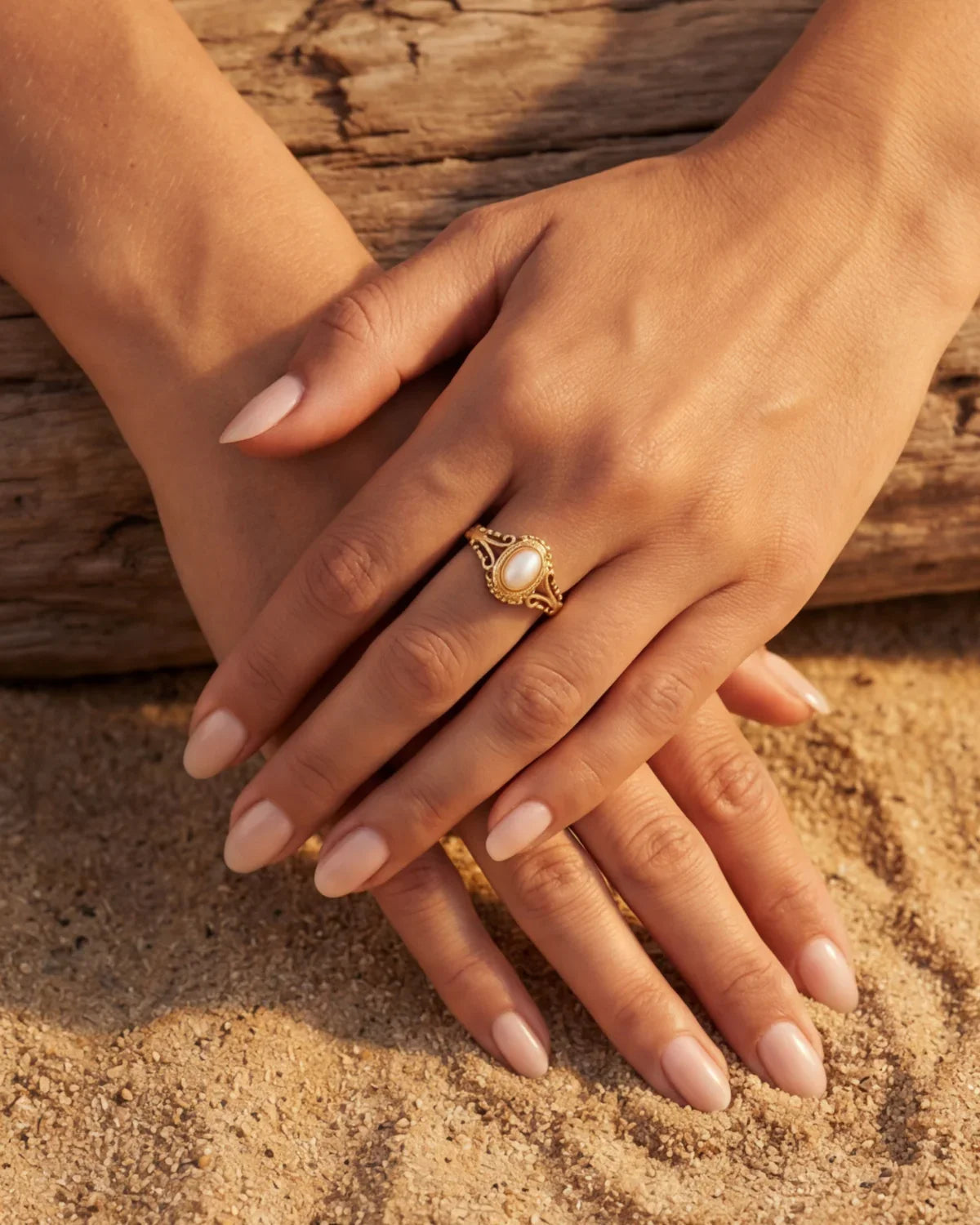 Gold oval-pearl ring on hand, halo-style filigree setting