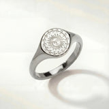 Silver-tone ring with oval sunburst engraving on the top and a smooth band