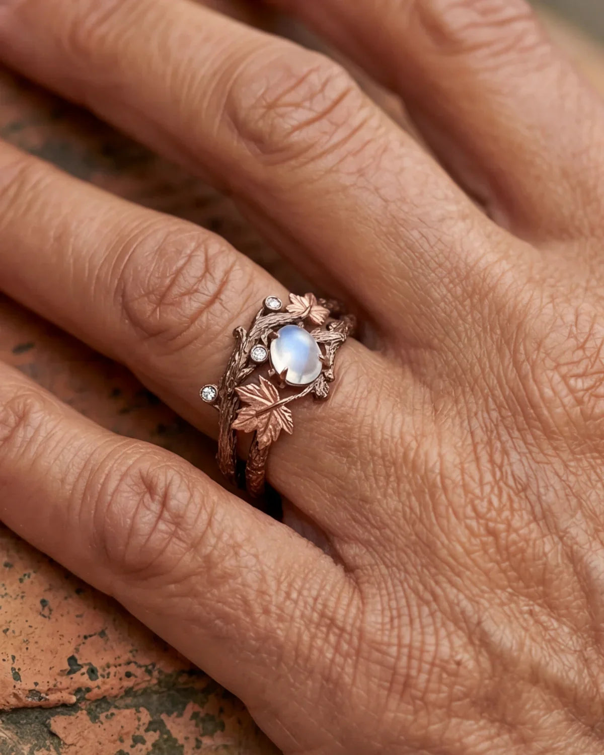 Bronze branch-effect ring with oval opalescent blue stone, leaf motif, and clear accents