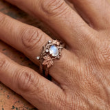 Bronze branch-effect ring with oval opalescent blue stone, leaf motif, and clear accents