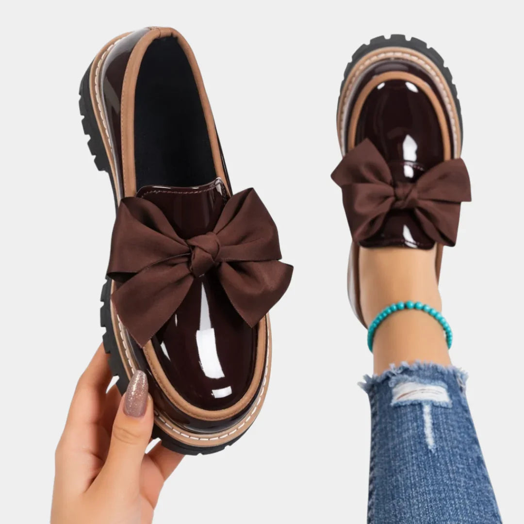 Brown heeled loafers with chunky sole and large brown bow accent