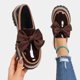 Brown heeled loafers with chunky sole and large brown bow accent