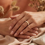Gold ring with small clear stones, shown on hands holding fabric