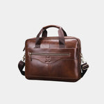 Caramel leather briefcase with top handle, zipper front pocket, and shoulder strap.