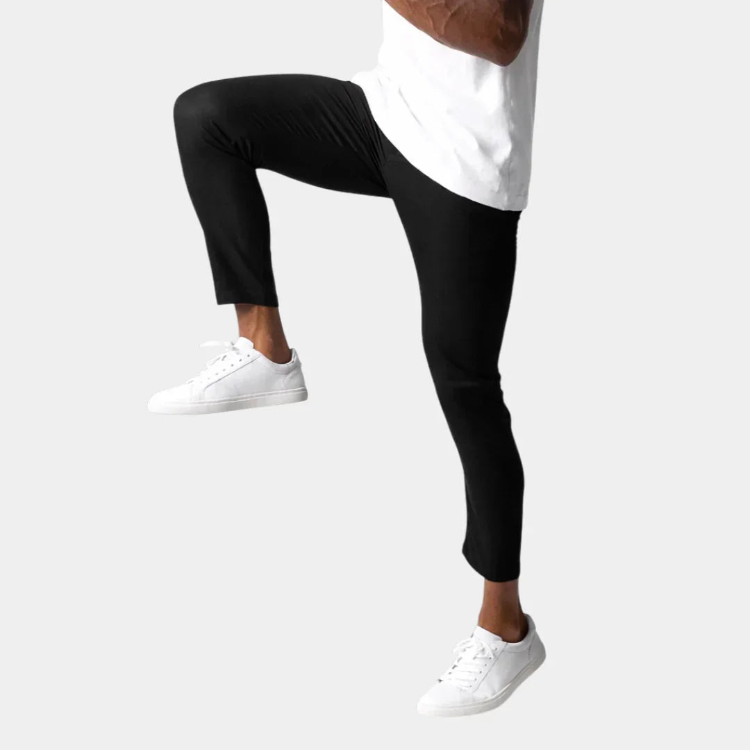 Black chino pants with slim fit and tapered leg, styled with white sneakers.