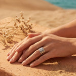 Silver ridged adjustable ring on hands on sand