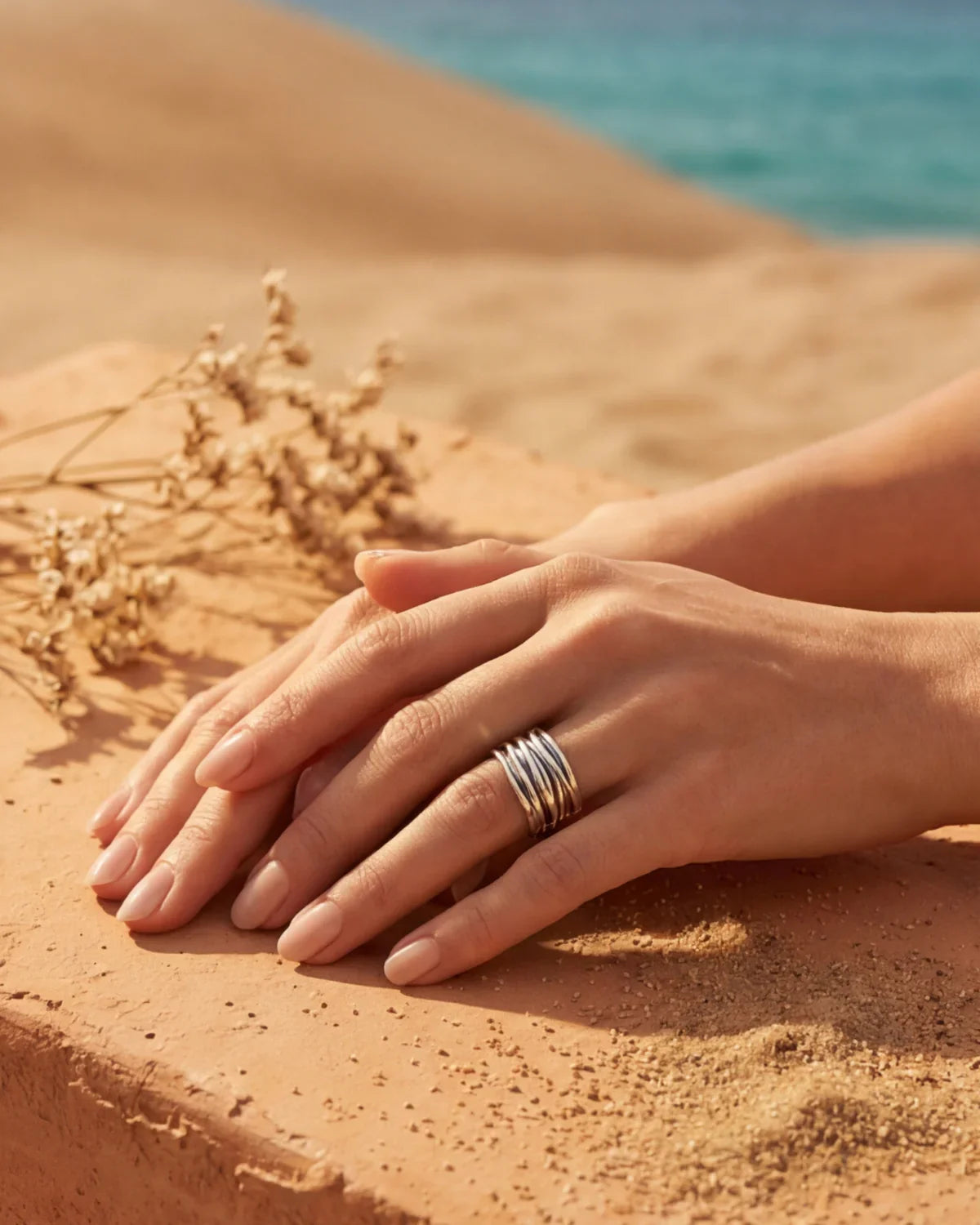 Silver ridged adjustable ring on hands on sand