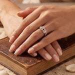Rose gold infinity ring with clustered sparkling stones, close-up on hand