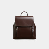 Dark brown leather backpack with top flap, handle loop, and two front zip pockets