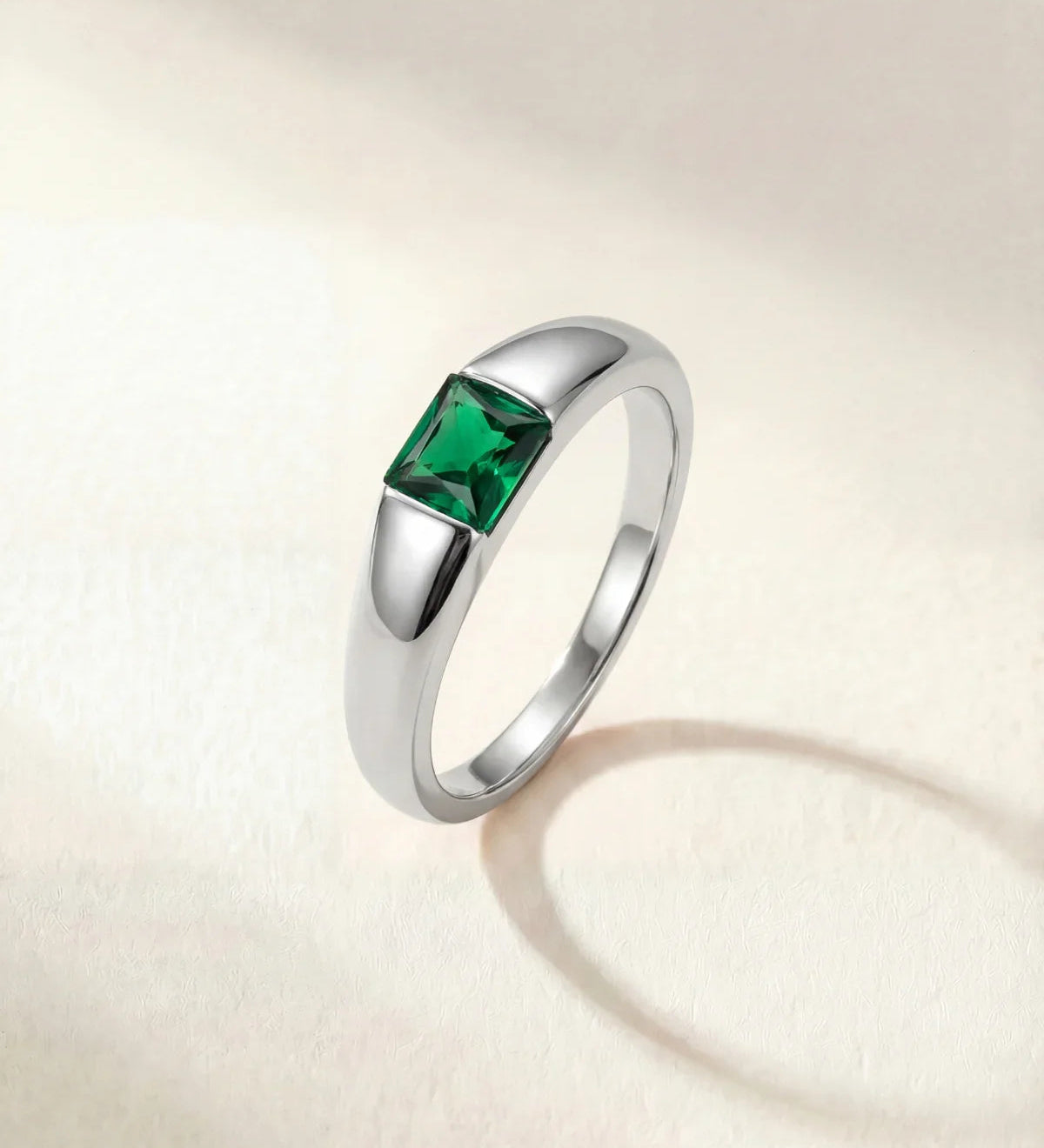Silver-tone ring with a square green gemstone set on a tapered band