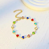 Gold-tone heart charm bracelet with colorful heart stones, chain loop flat lay